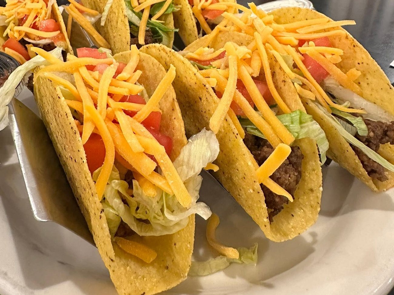 Hard shell beef tacos with lettuce, tomato and cheddar