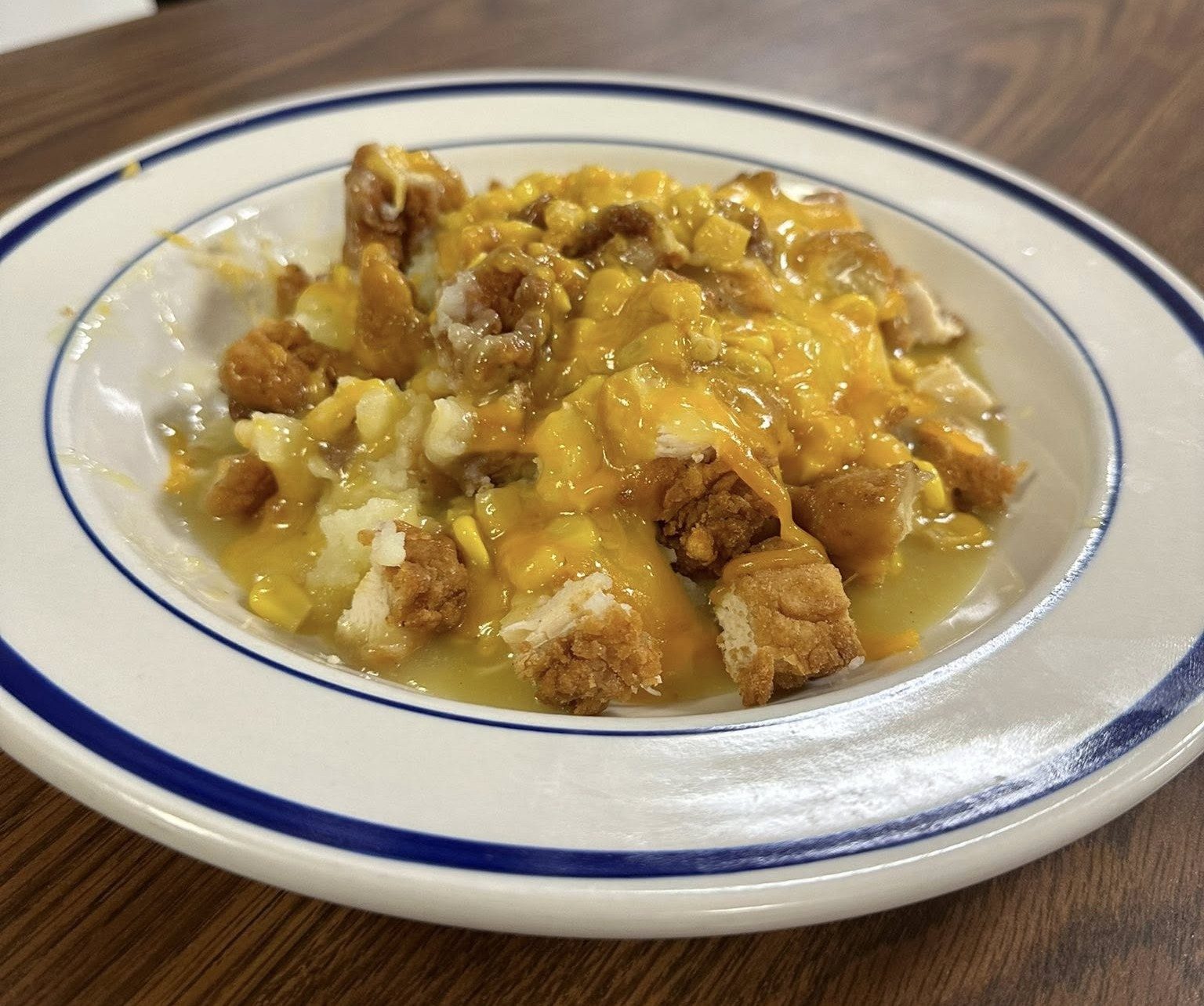 Fried chicken over mashed potatoes, corn and cheese