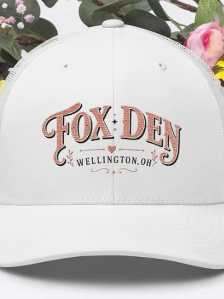 White trucker cap with Fox Den Wellington, OH embroidered in script
