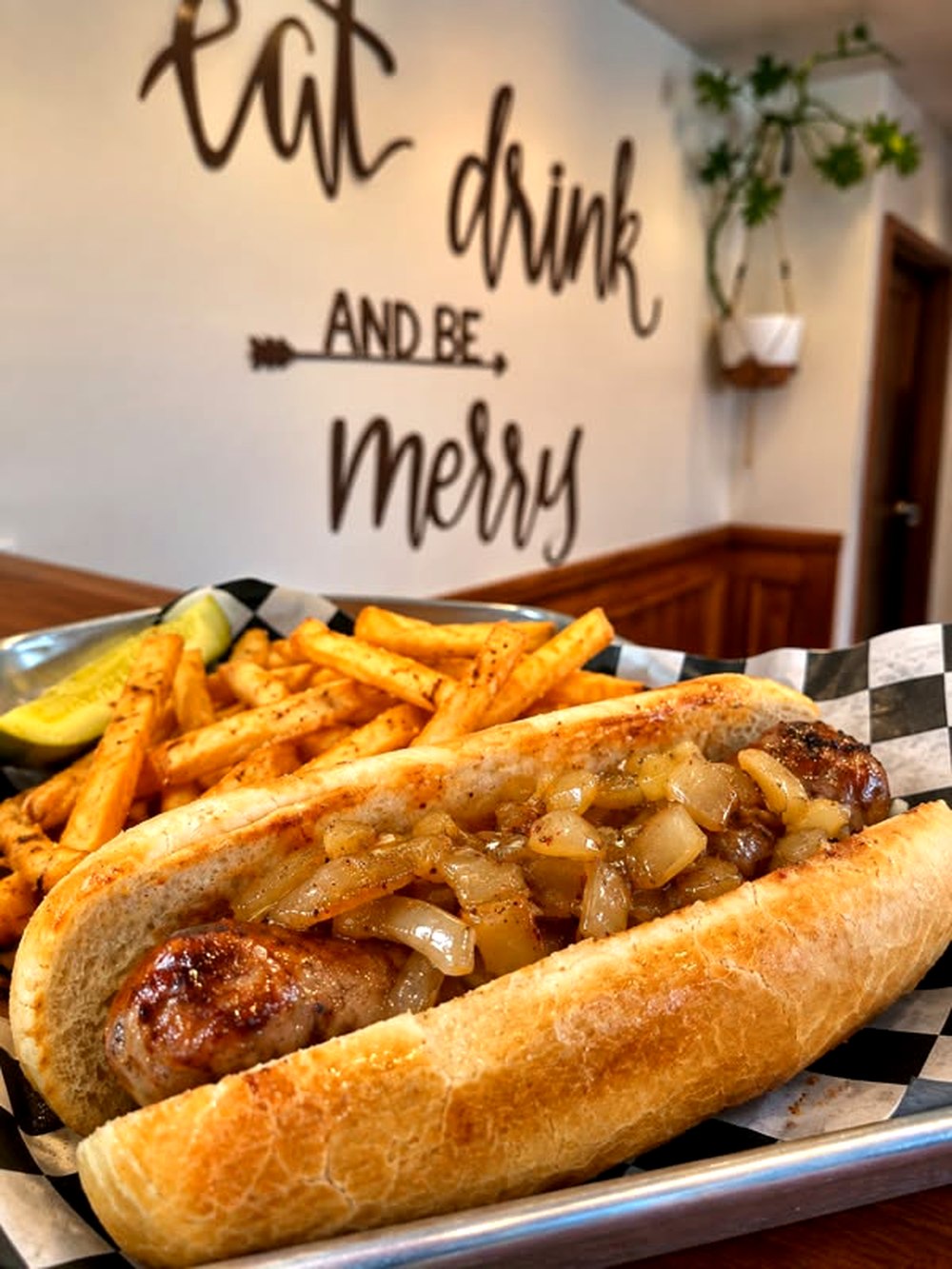 Apple glazed bratwurst in a hoagie roll with grilled onions, fries and a pickle