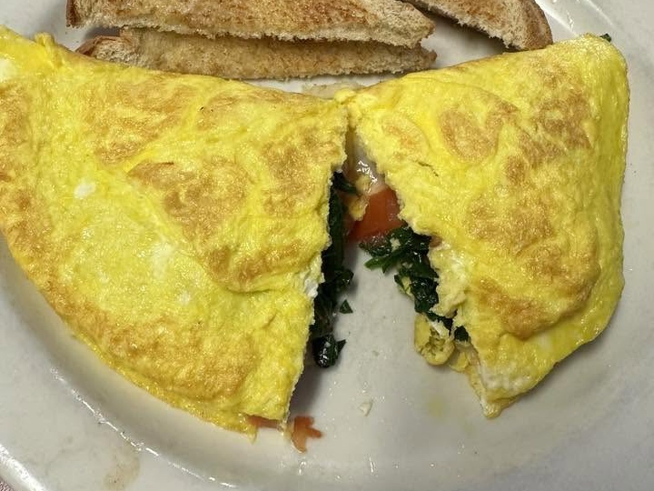 Omelette with spinach and tomato served with toast