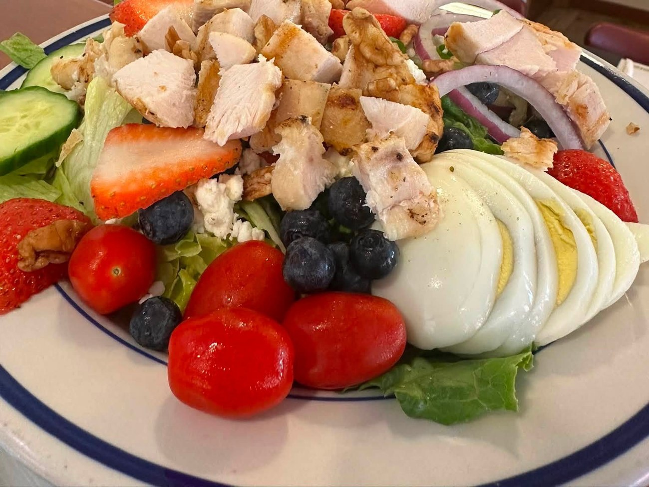 Grilled chicken salad with strawberries, blueberries, walnuts and egg