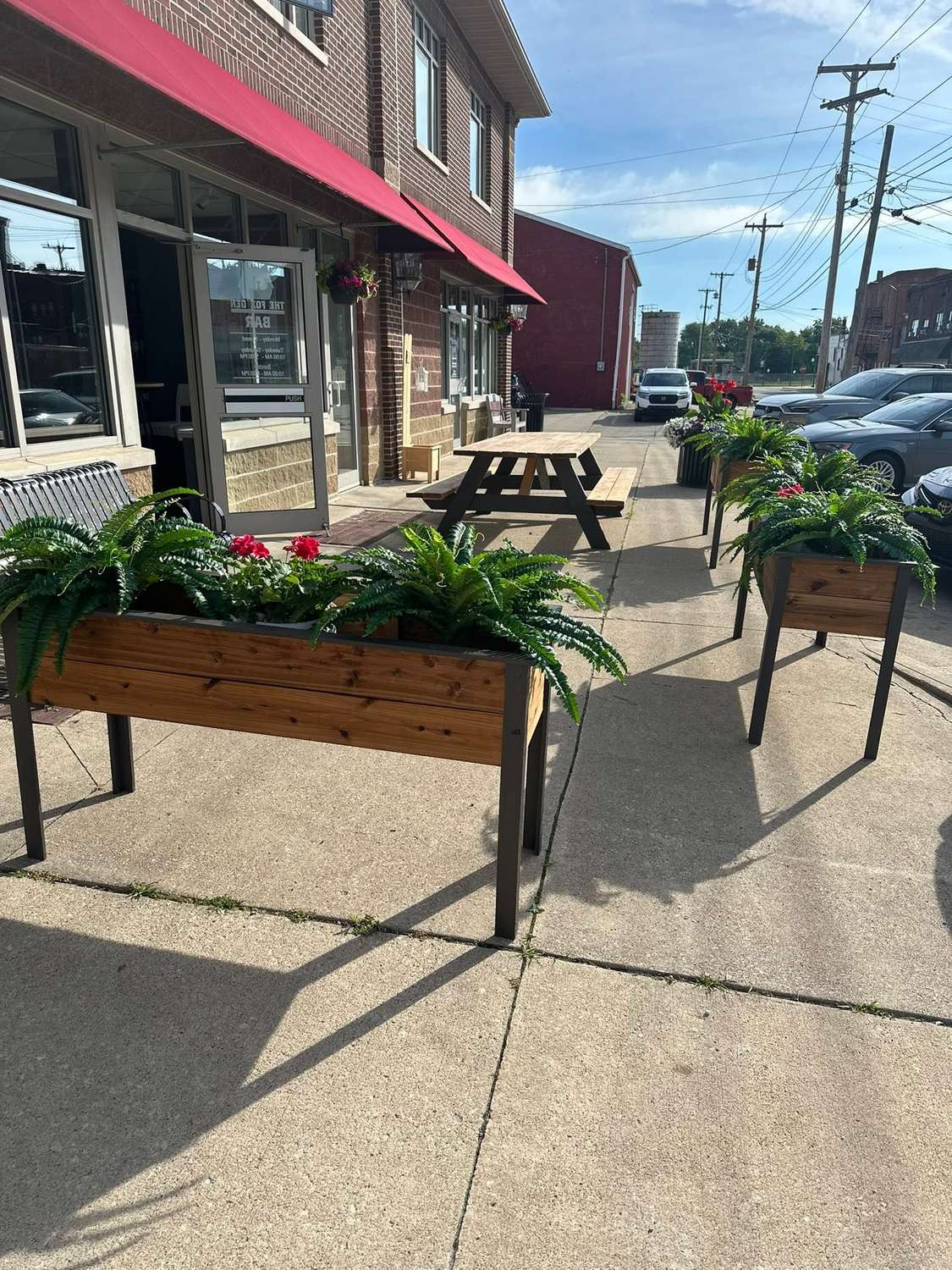 The Fox Den patio with red awnings, string lights and flower planters