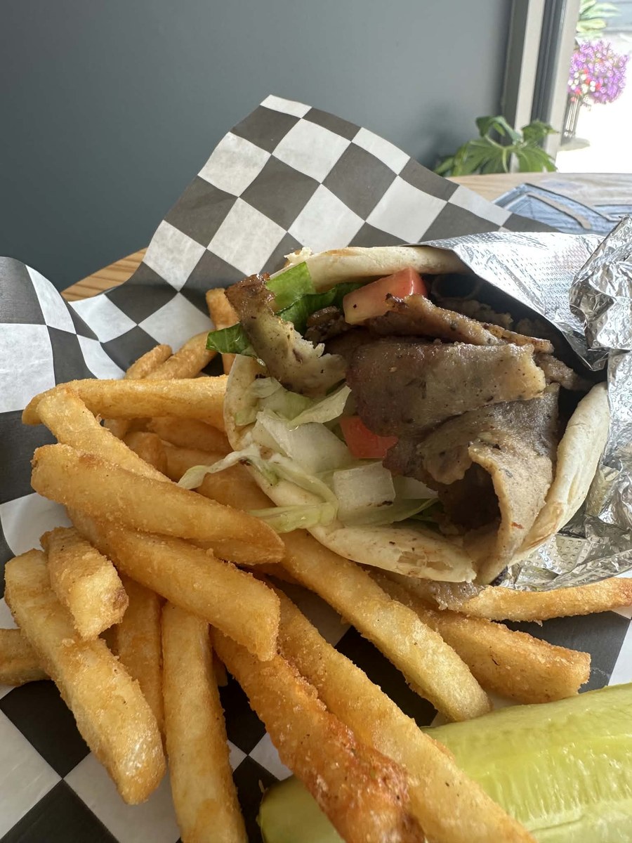 Lamb gyro in pita with lettuce, tomato and onion, served with fries and a pickle