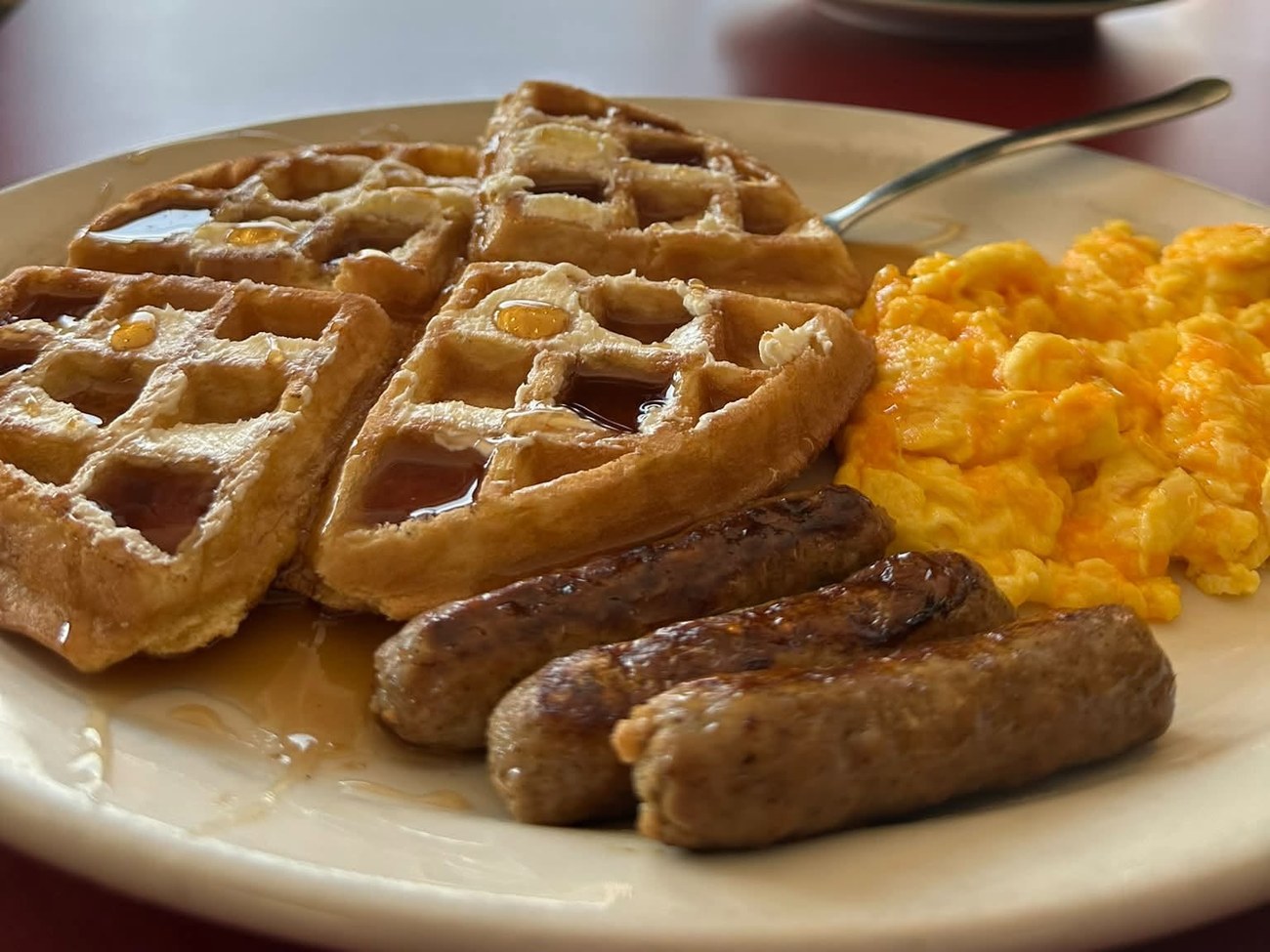 Waffles with syrup, scrambled eggs and sausage links